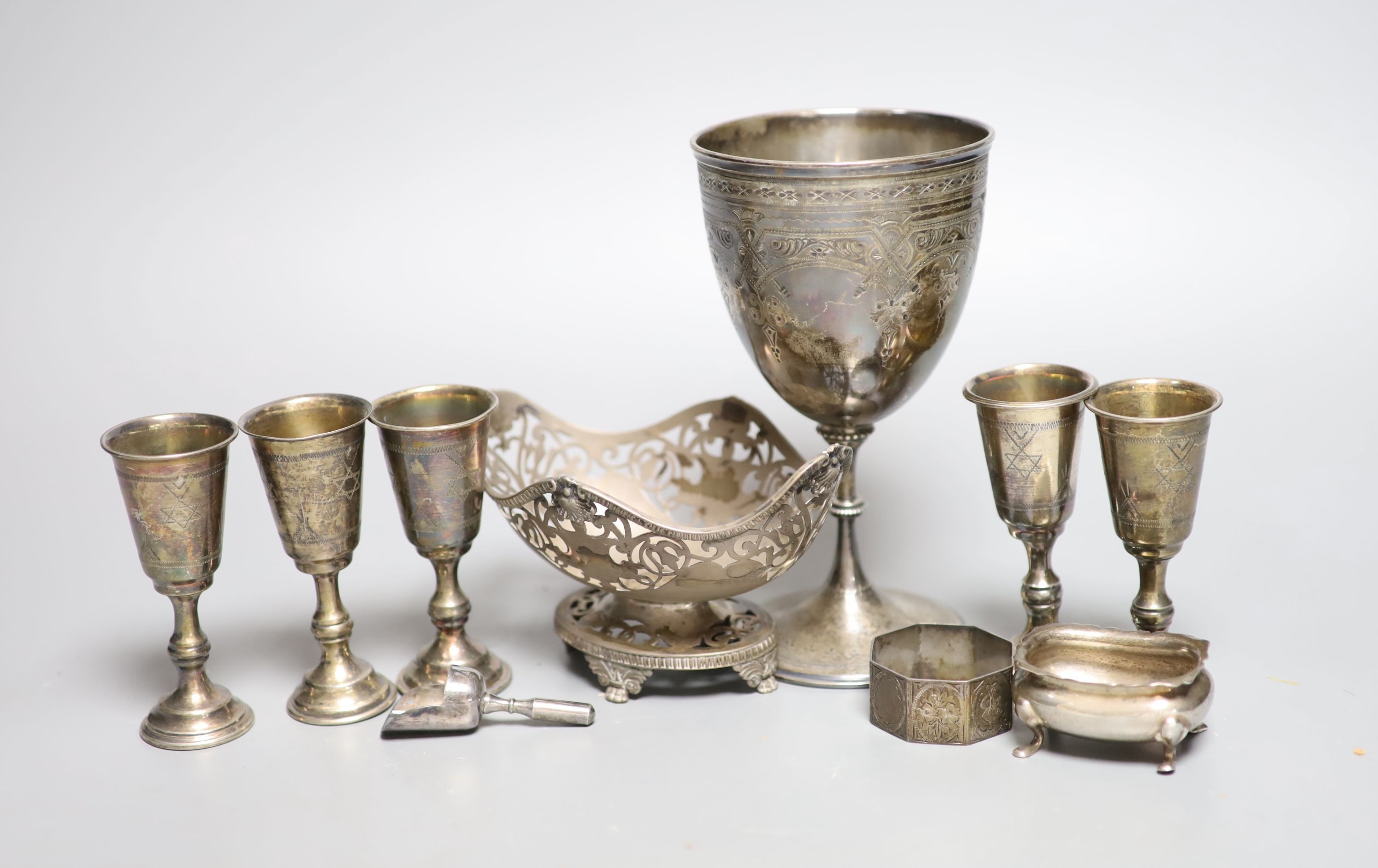 Five George V silver kiddush cups, a late Victorian silver goblet, a silver bonbon dish, silver salt, silver napkin ring and a plated sugar shovel